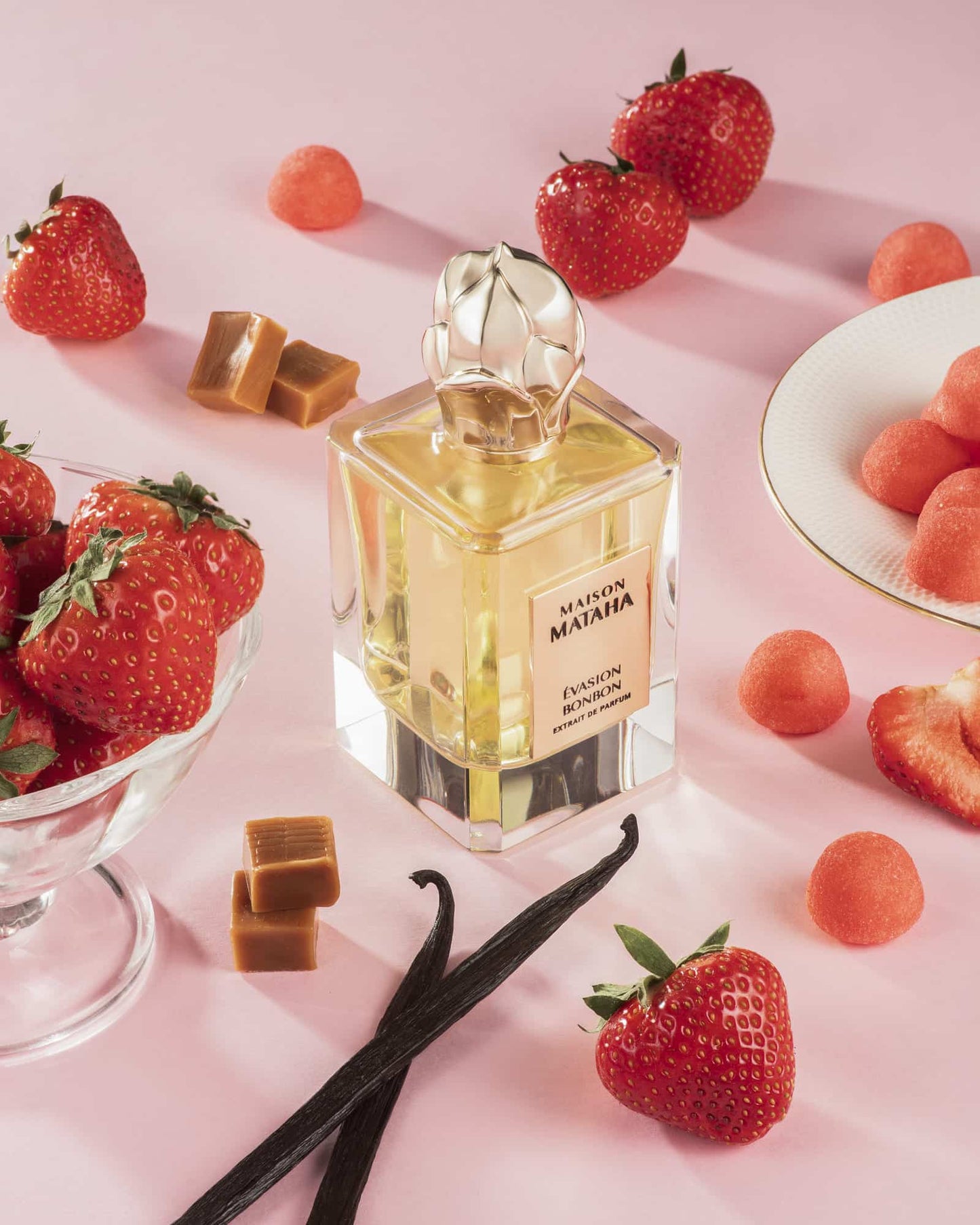 Flacon de parfum en verre evasion bonbon en extrait de parfum avec un fond rose et des bonbon